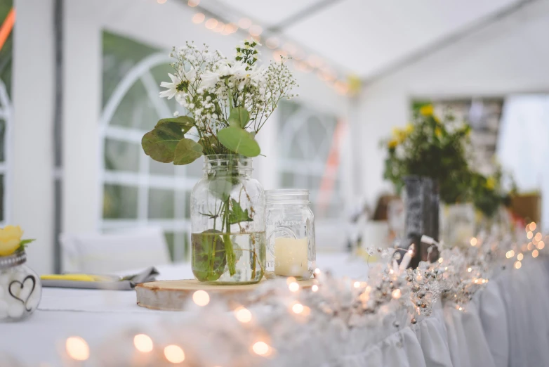 some jars and flowers sitting on a table with lights