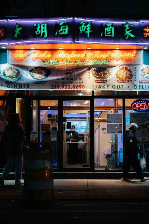 people standing outside of a restaurant at night