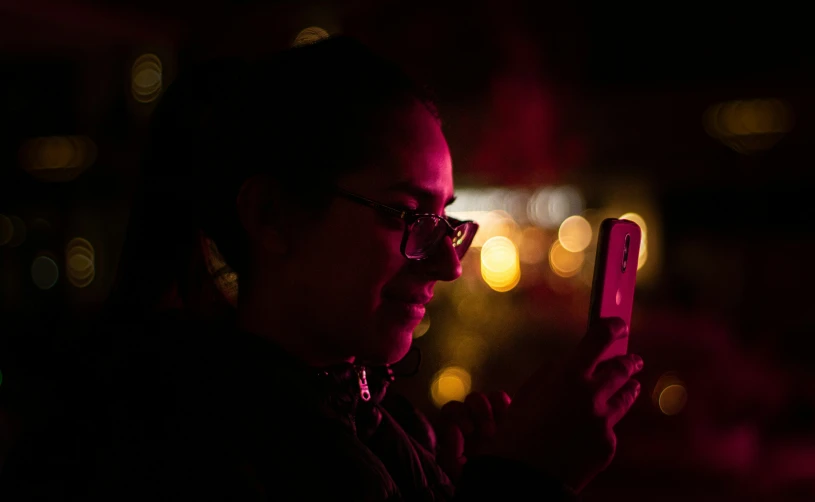 a person with glasses holding a cell phone