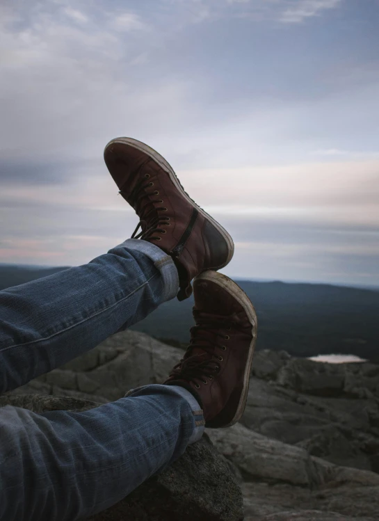 someone sitting on a rock with their feet propped on it