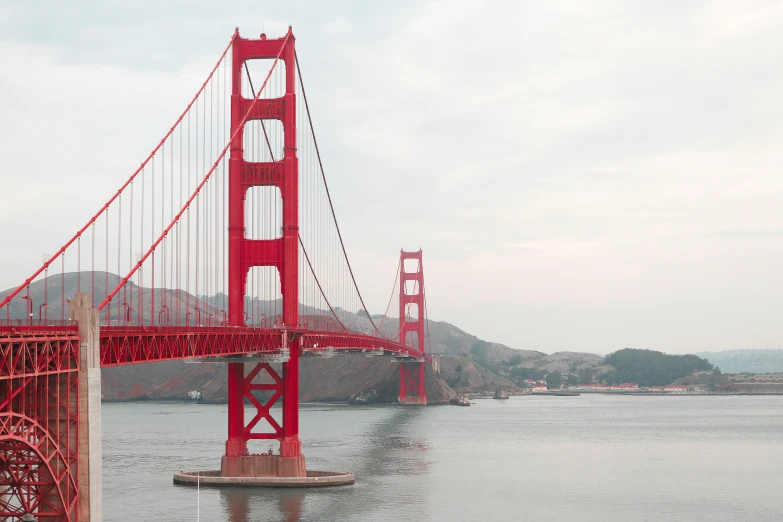 a tall red bridge is spanning a river