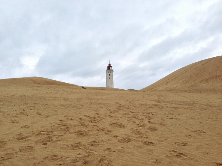 a small lighthouse tower sticking out of a sand dune