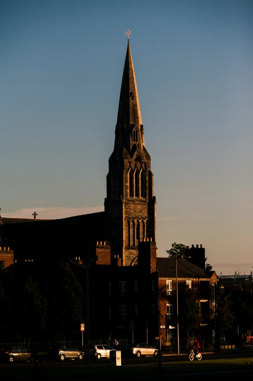 large stone building with steeple with cars and motorcycles