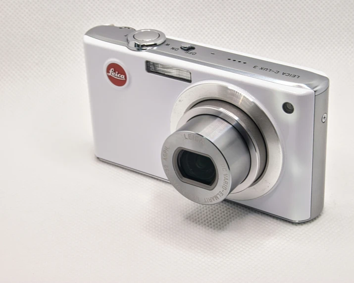 an old fashioned silver digital camera on a white surface