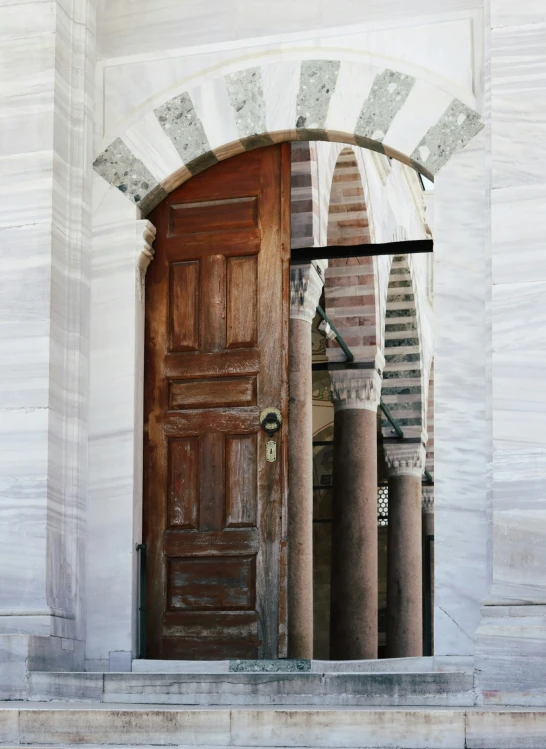 an arched door leading into a building with columns and a round window