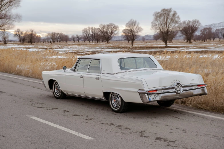 an old classic car traveling down a snowy road