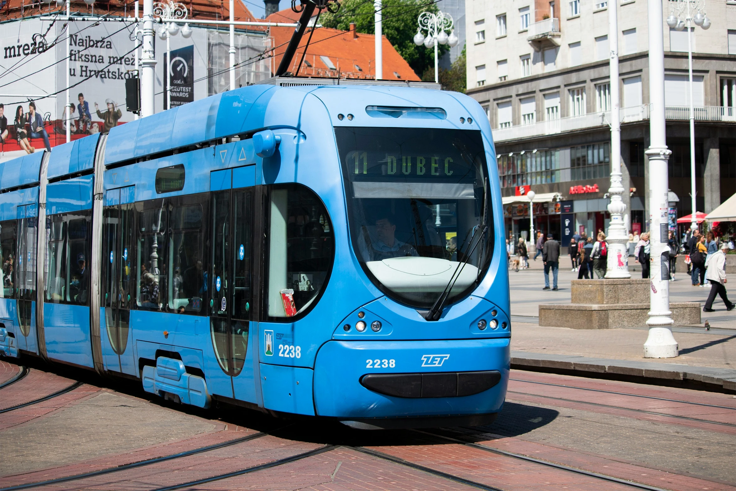 there is a blue bus going down the street