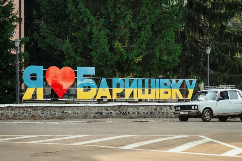 an empty car driving through a road in front of a giant sign