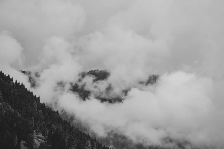 some very thick clouds near a mountain with a plane flying above