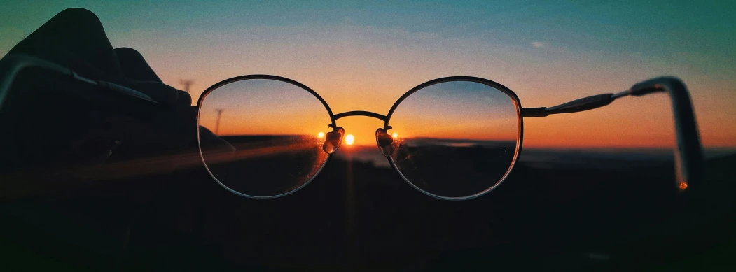 the sun rises through two glasses in front of mountains