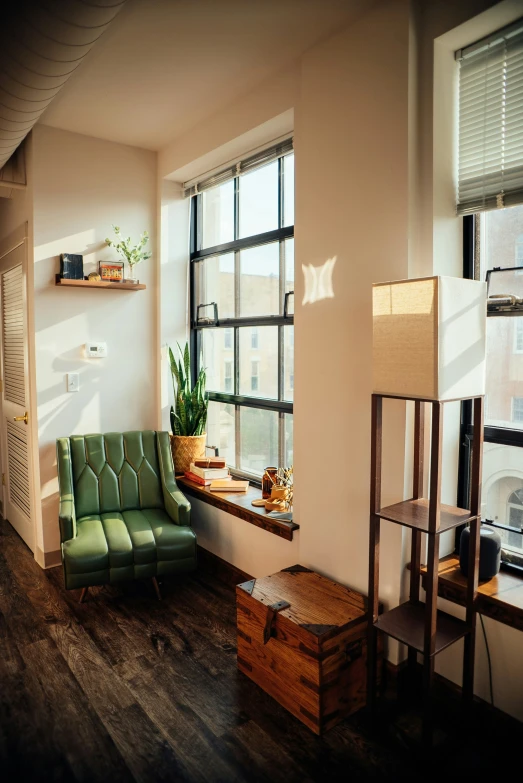 an empty living room with green chairs and windows