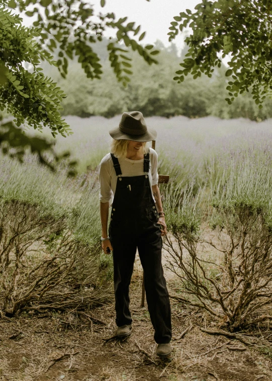 a woman is standing on the dirt in a hat