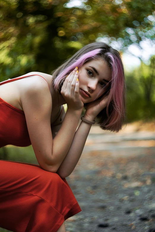 a woman in a red dress is crouching on a path