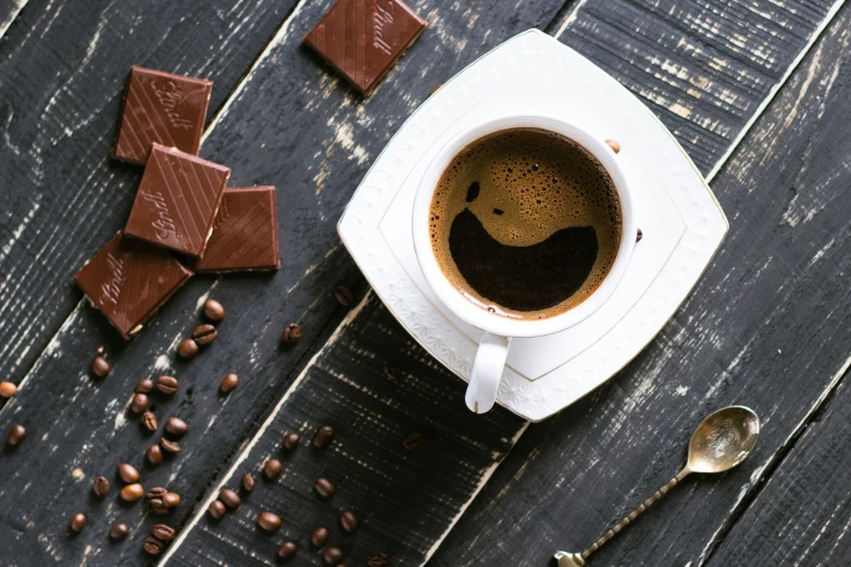 a coffee cup and some chocolate squares on the table