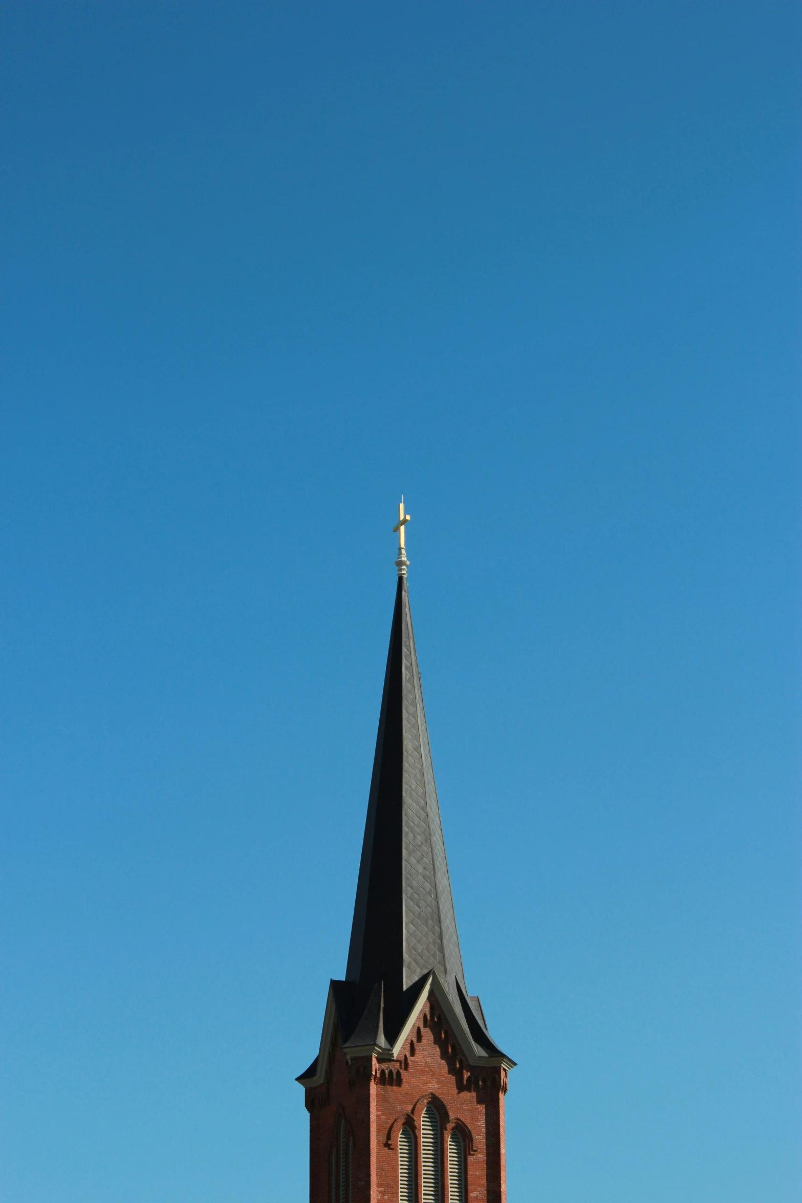 the steeple of an old brick church with a clear blue sky