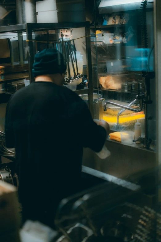 a man working inside a restaurant kitchen and frying chicken