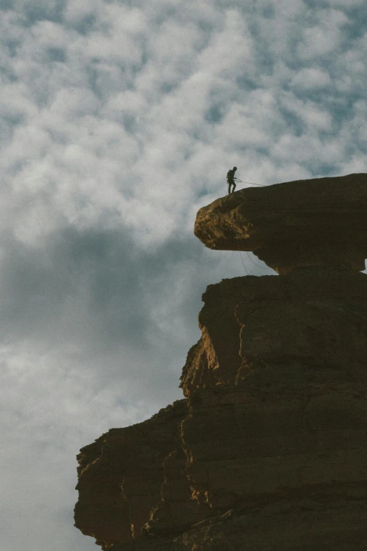 a lone person standing at the top of a large cliff