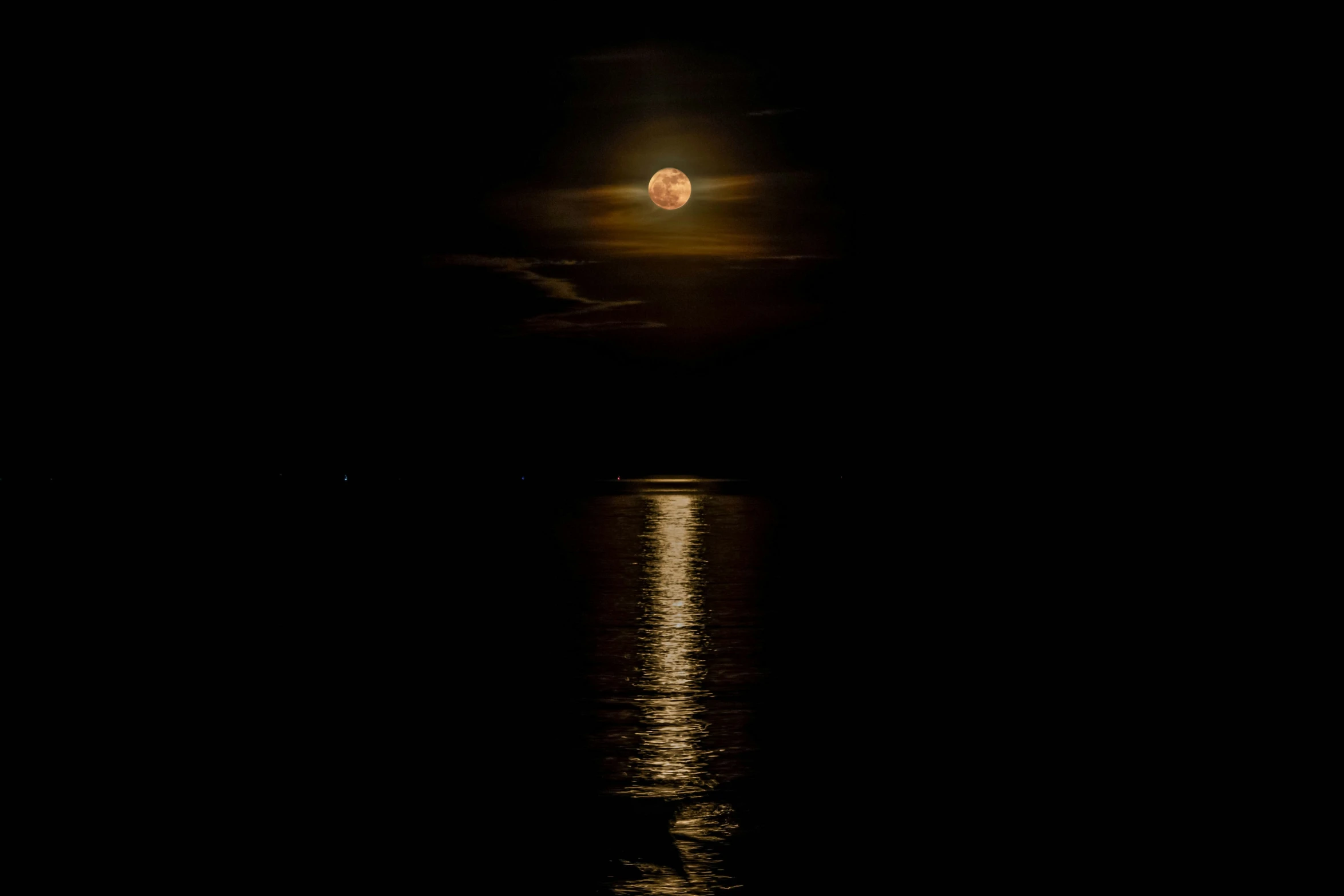 the moon is rising over the water at night