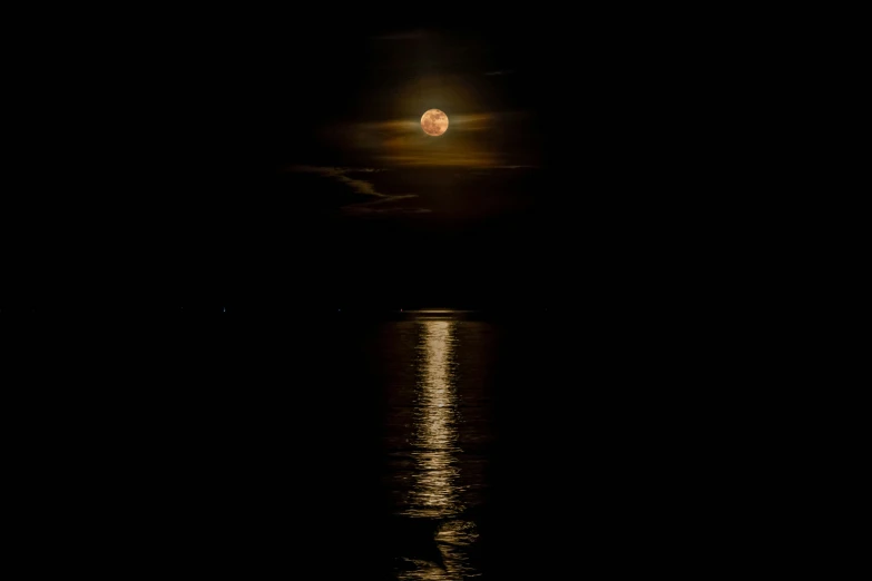 the moon is rising over the water at night