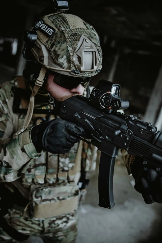 a man in camouflage holding a rifle with a video camera on it