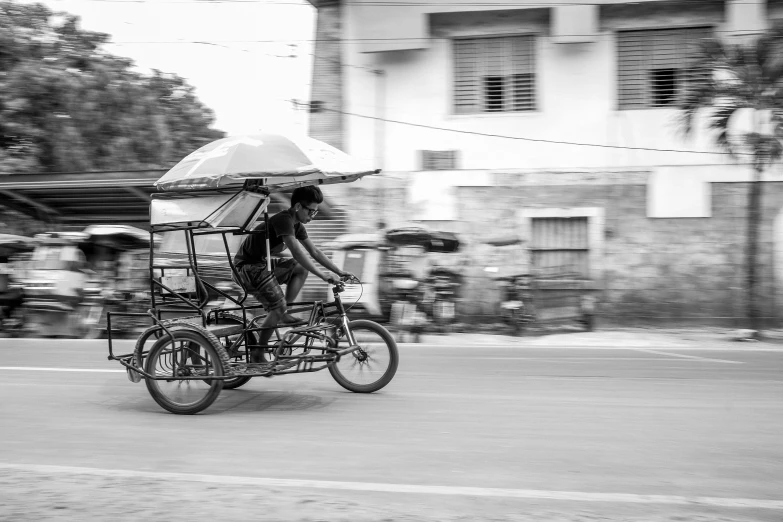 a man riding a bike down a street holding an umbrella