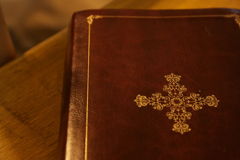 an old brown book with a gold cross on the front