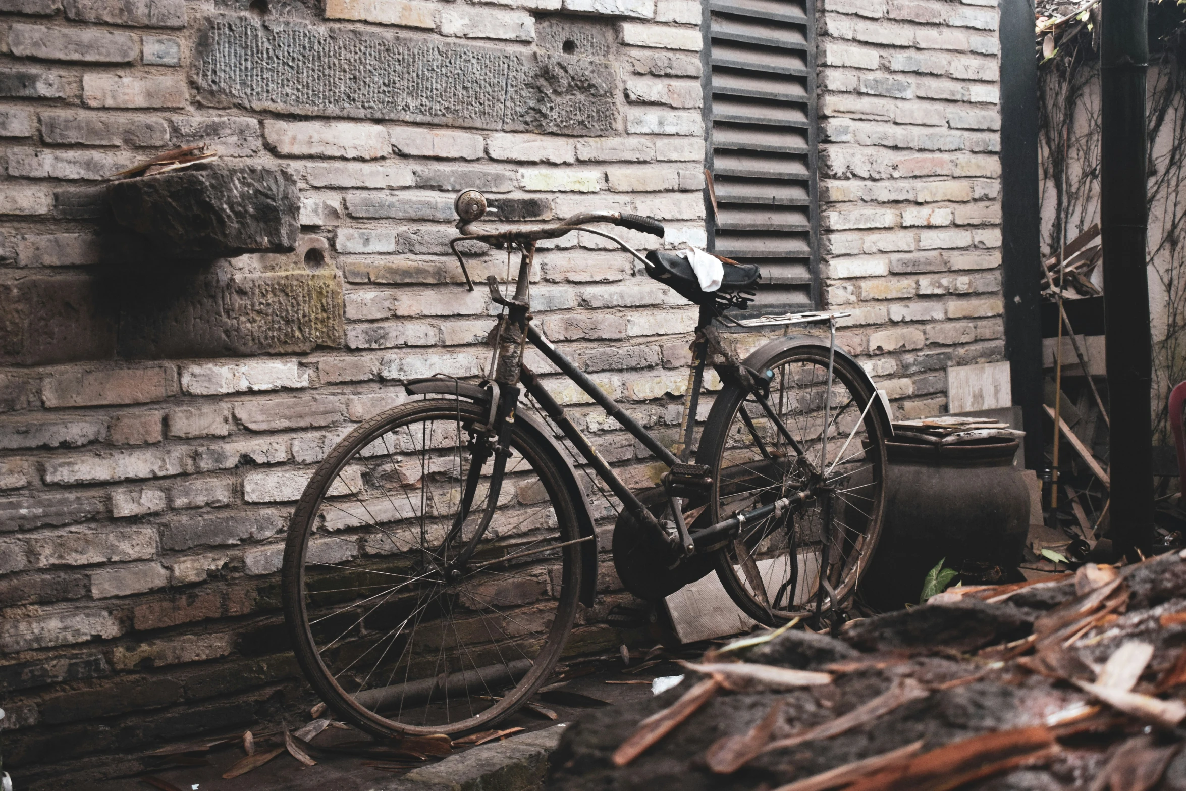 a bike leaning against a brick wall near trash cans