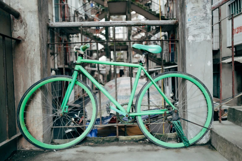 a green bike locked to the side of a building