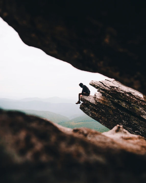 a person sitting on a tree trunk while looking out at mountains