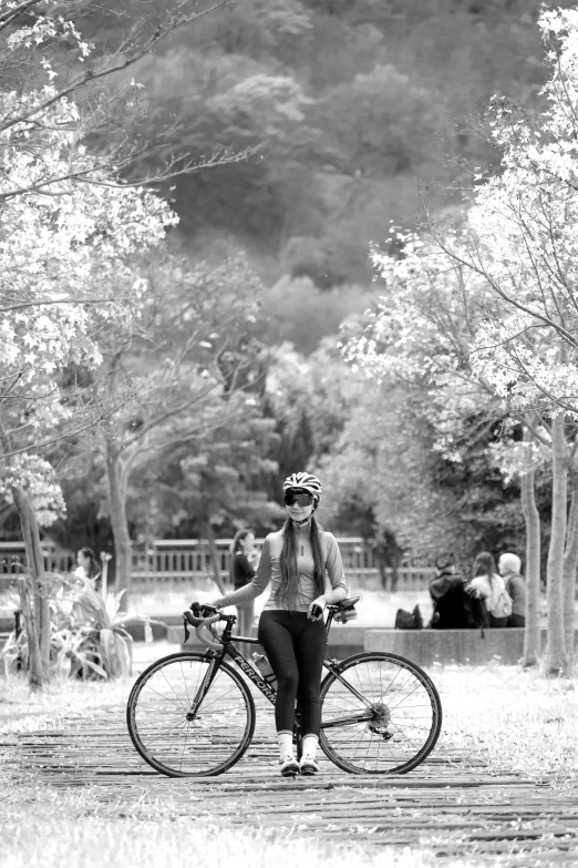 a woman riding on the back of a bike next to trees