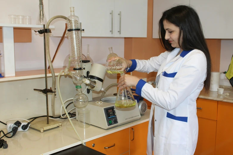 a woman standing in a laboratory pouring liquid