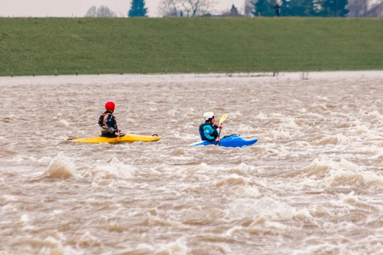 two people are riding kayaks in some dirty water