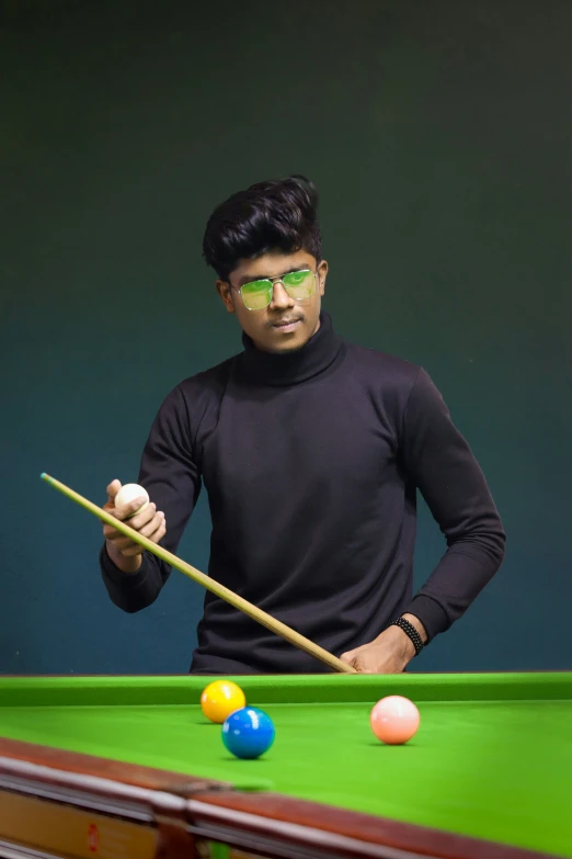 a man with glasses is holding a pool stick and balls