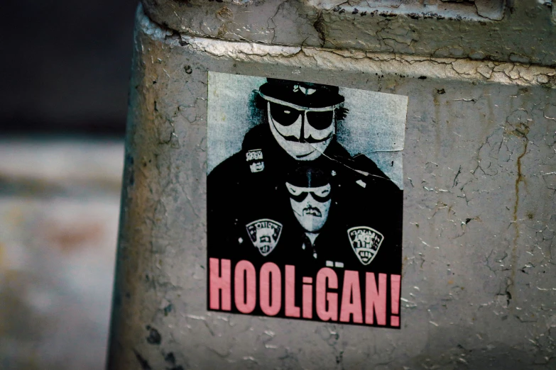 a sticker is on a pole with the word hooligan