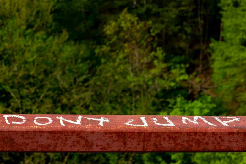 there is a red bench sitting alone with some writing