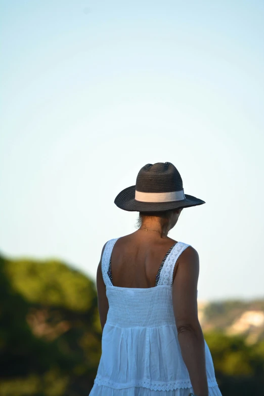 the woman in a hat is looking out over a field