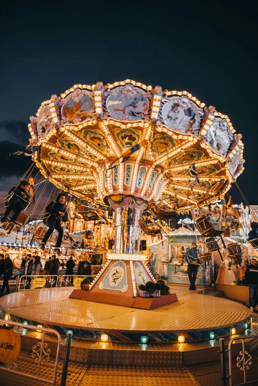 a fairground with a carousel, two people and lights on