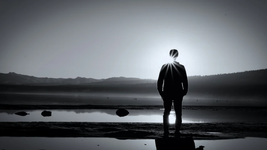 man staring at misty lake in the distance