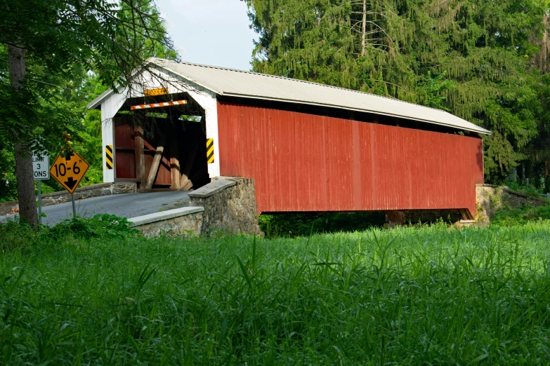 a red covered bridge crossing over green grass