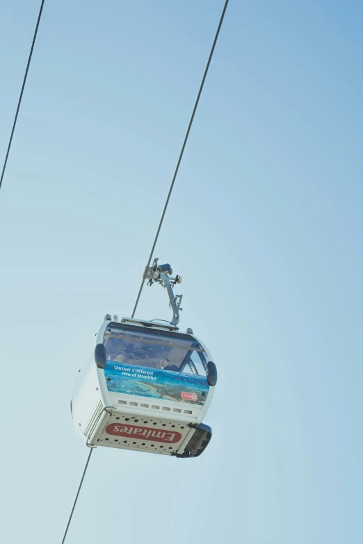 a cable car with people below and in the background