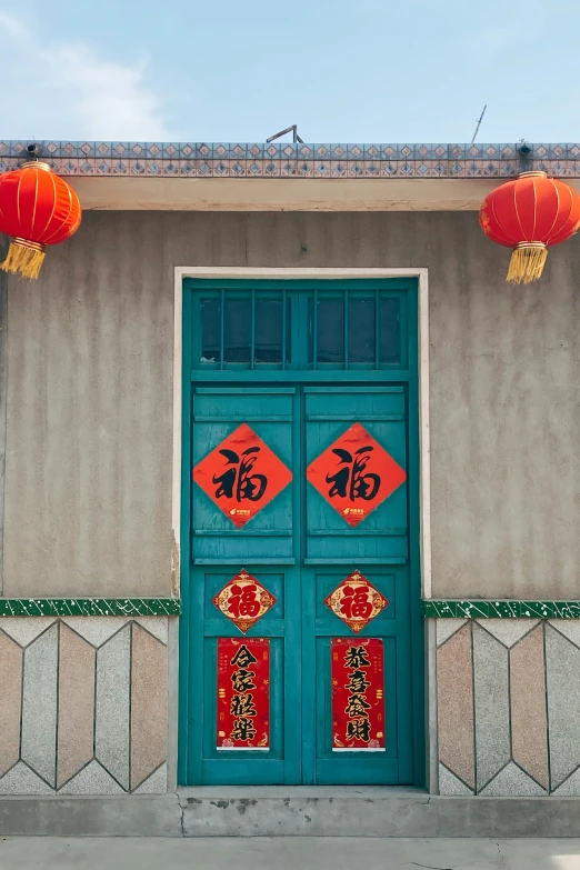 two red lanterns are above a door with blue doors