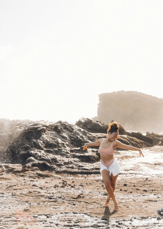 a woman in white shorts and a  shirt running on a beach