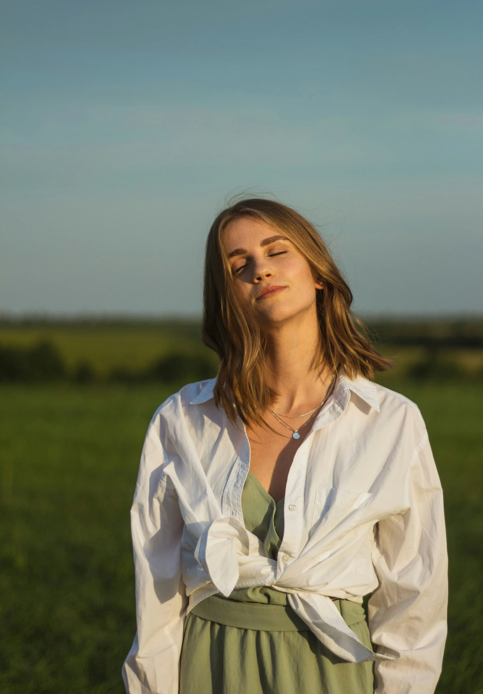 a woman in a white shirt stands in a field