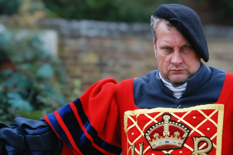 an older man with a red coat, and gold collared shirt