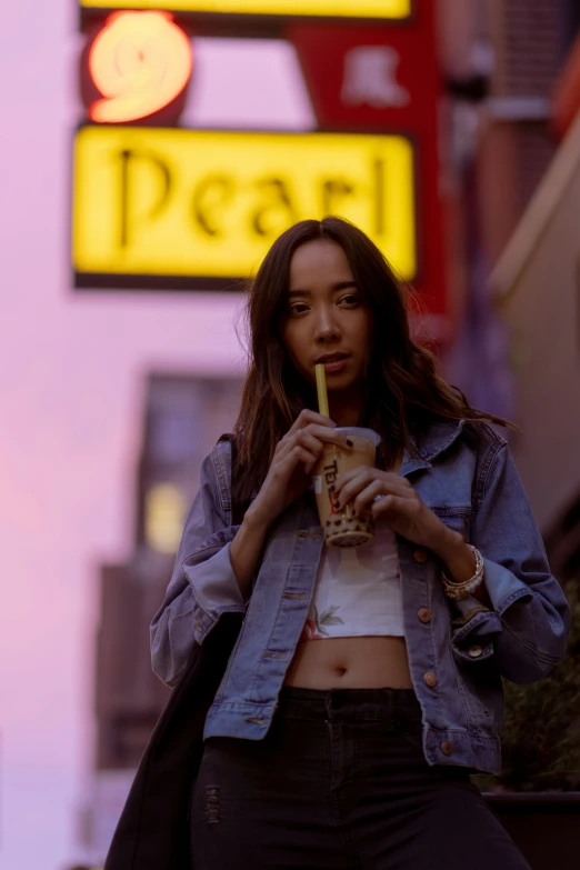 a woman holding a drink walks down the street