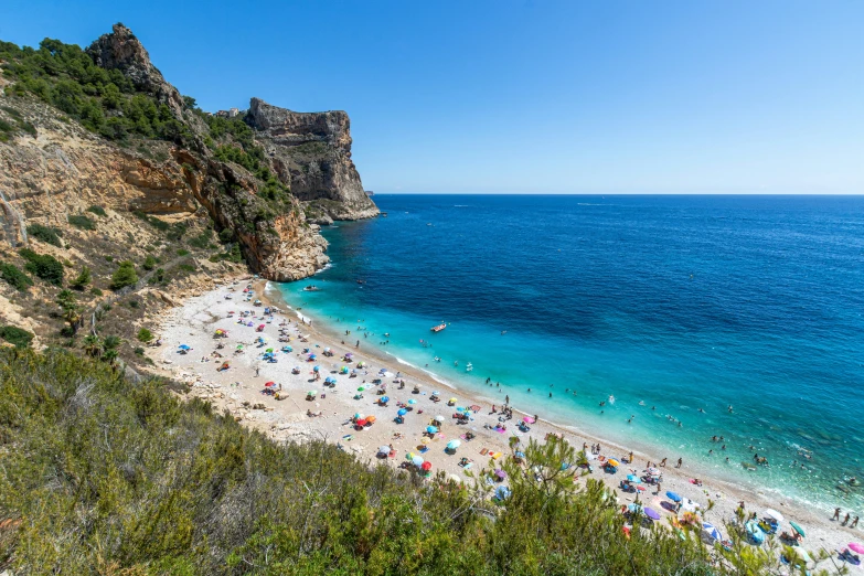 a crowded beach with people on it next to an ocean