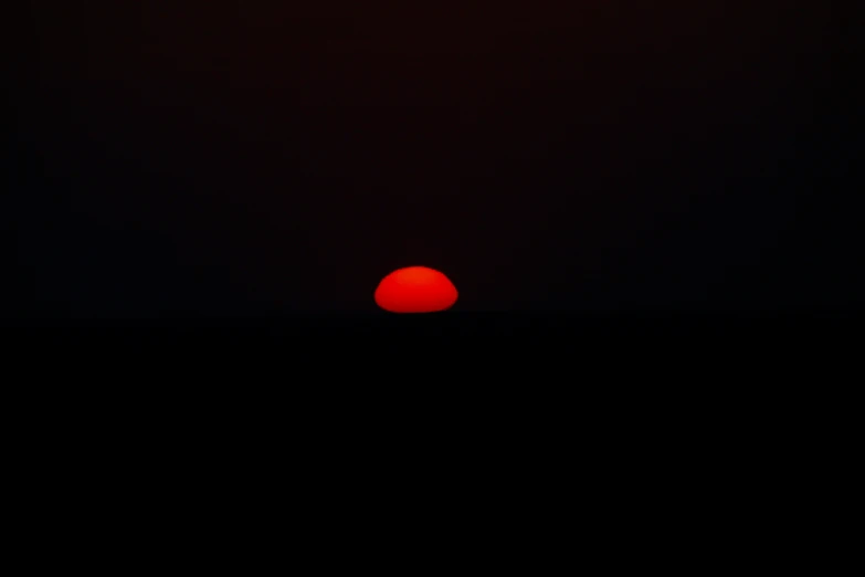 a red sun shining on the horizon in black sky