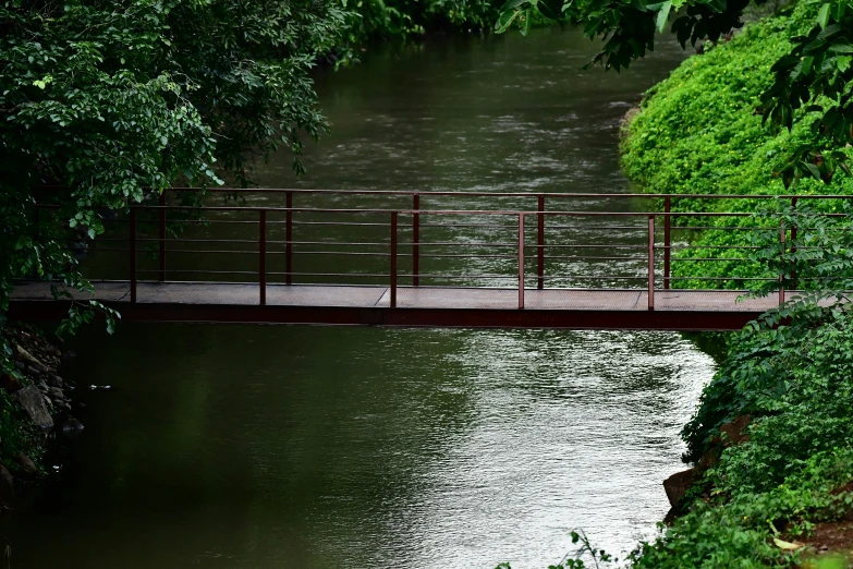 a person in orange rain gear stands on a bridge over the water