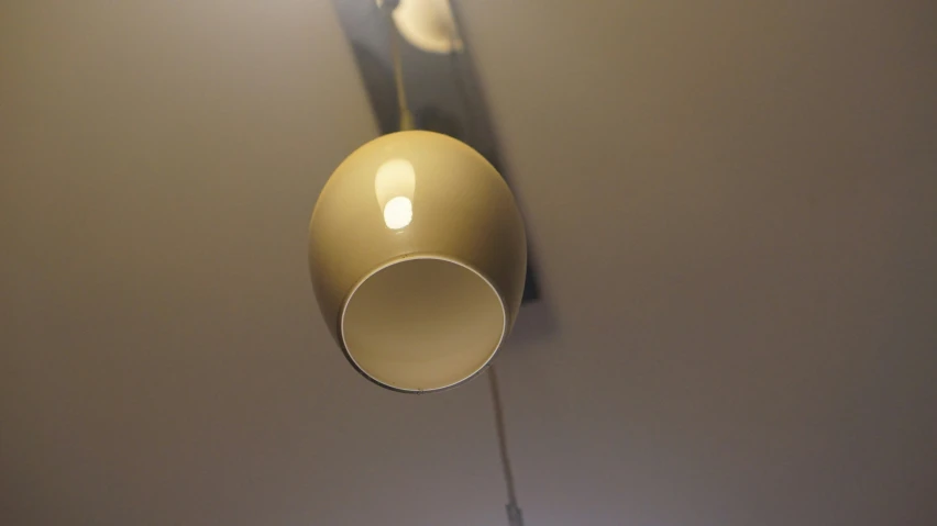 a gold lamp hanging from the ceiling against a gray background