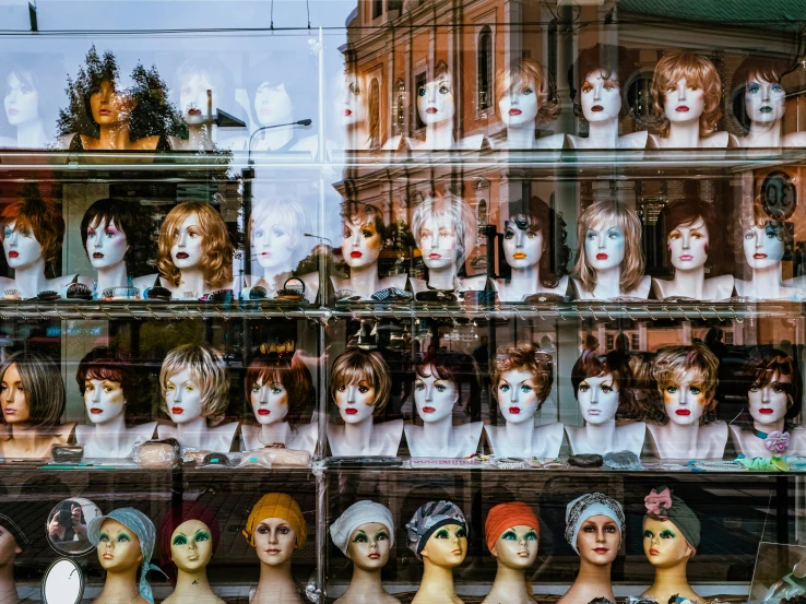 many mannequins are in a row behind glass